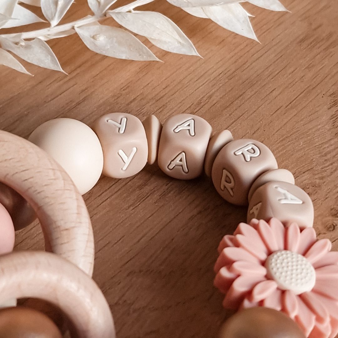 Bijtring met naam madelief in de kleur zalmroze handgemaakt door Iris van Studio Bambacht