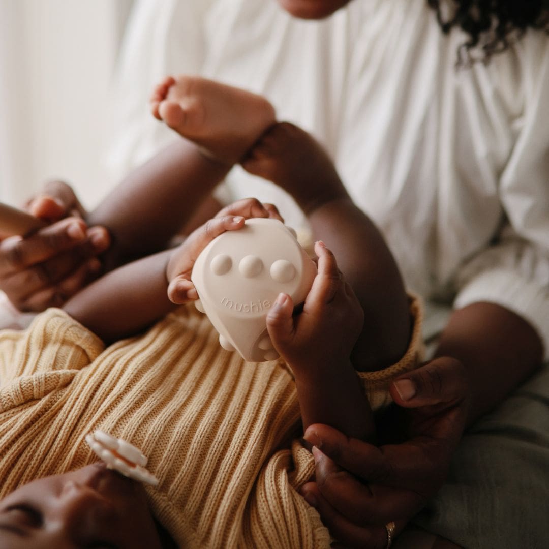 Mushie bijtspeelgoed press toy dobbelsteen shifting sand wit en blush roze