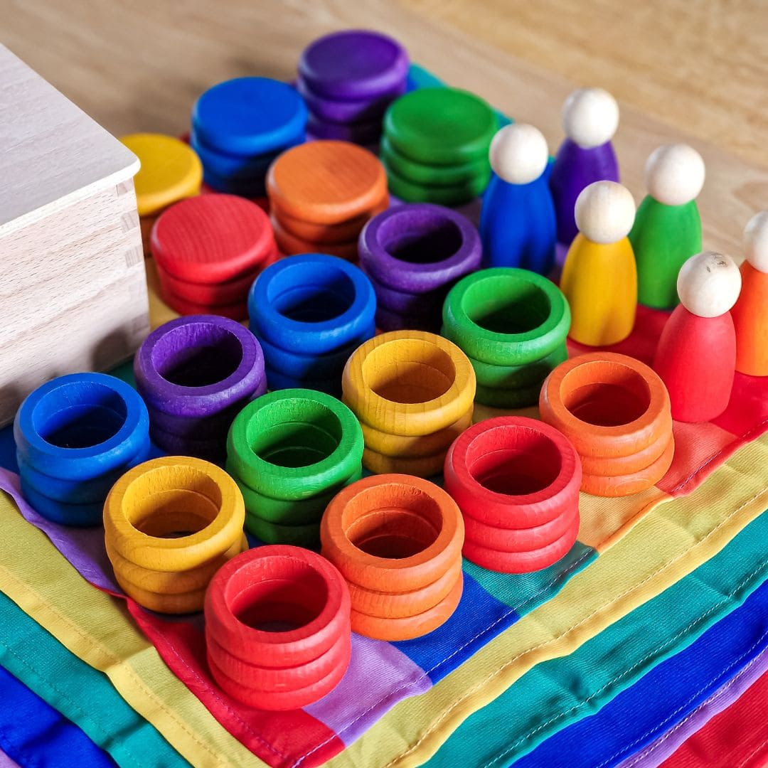 Open einde starterspeelset voor 0-2 jaar met objectpermanentiebox, speeldoek en grapat houten ringen, munten en poppetjes om objectpermantie te stimuleren en uit te nodigen tot fantasierijk en zelfstandig spel