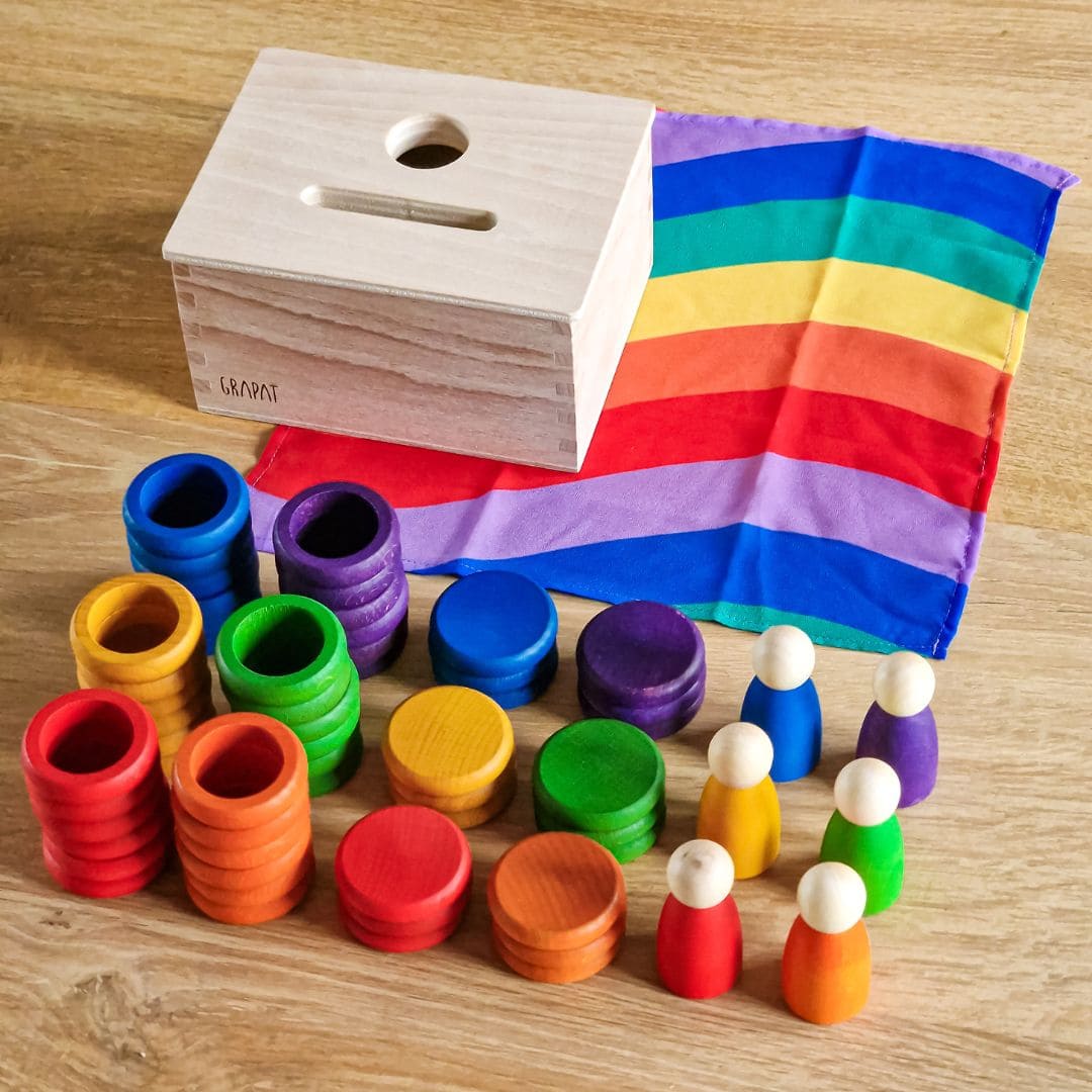 Open einde starterspeelset voor 0-2 jaar met objectpermanentiebox, speeldoek en grapat houten ringen, munten en poppetjes om objectpermantie te stimuleren en uit te nodigen tot fantasierijk en zelfstandig spel