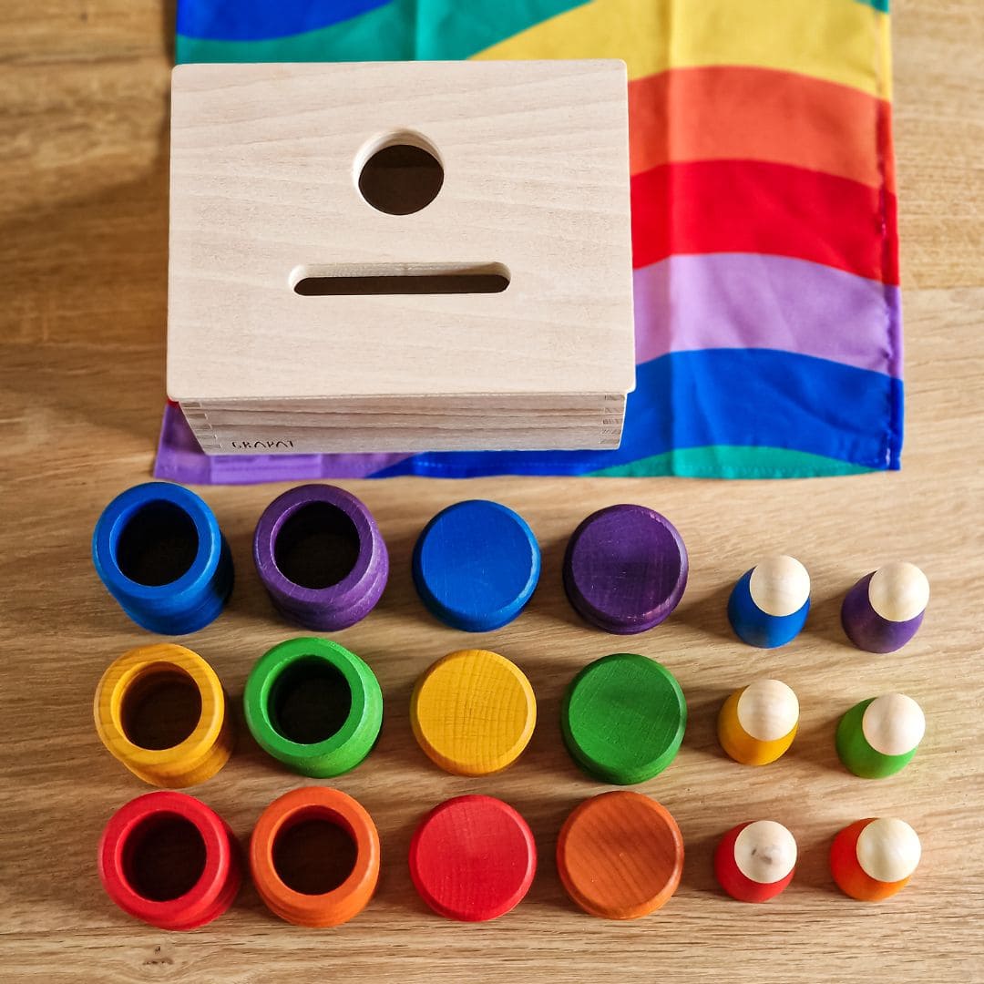 Open einde starterspeelset voor 0-2 jaar met objectpermanentiebox, speeldoek en grapat houten ringen, munten en poppetjes om objectpermantie te stimuleren en uit te nodigen tot fantasierijk en zelfstandig spel