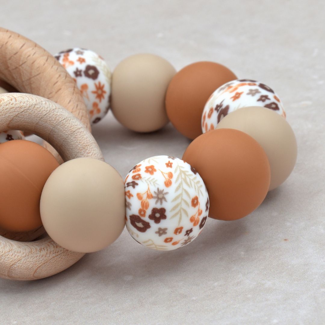 Bijtring van Studio Bambacht met bloemenprint in de kleur roest en beige en twee houten ringen