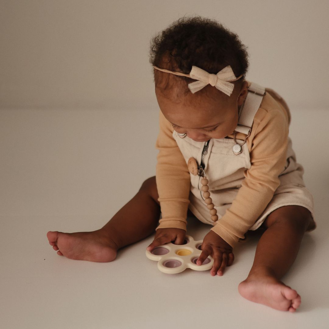 Mushie sensorisch speelgoed press toy bloem lila en geel