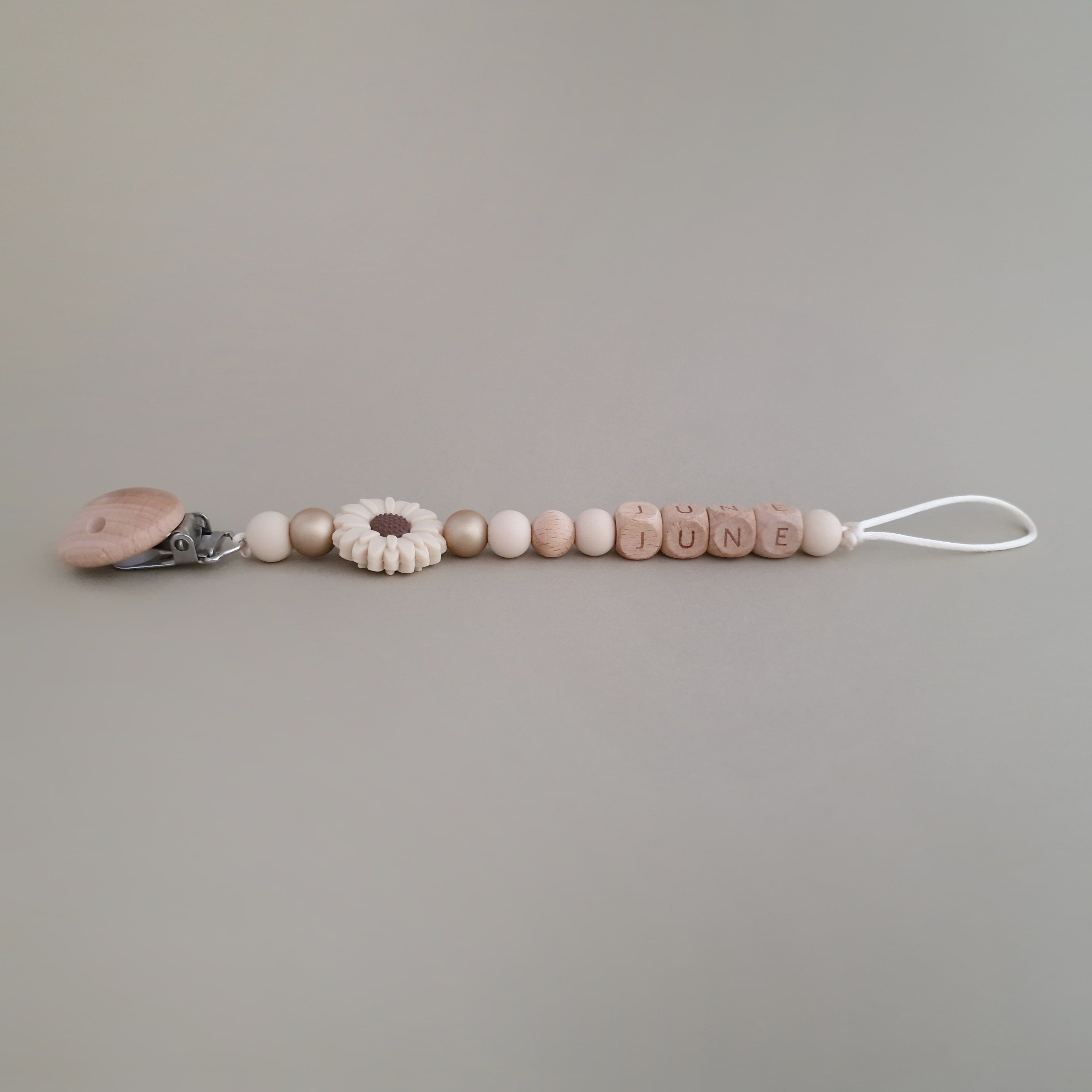 Speenkoord met naam van Studio Bambacht met bloem in de kleuren beige en goud