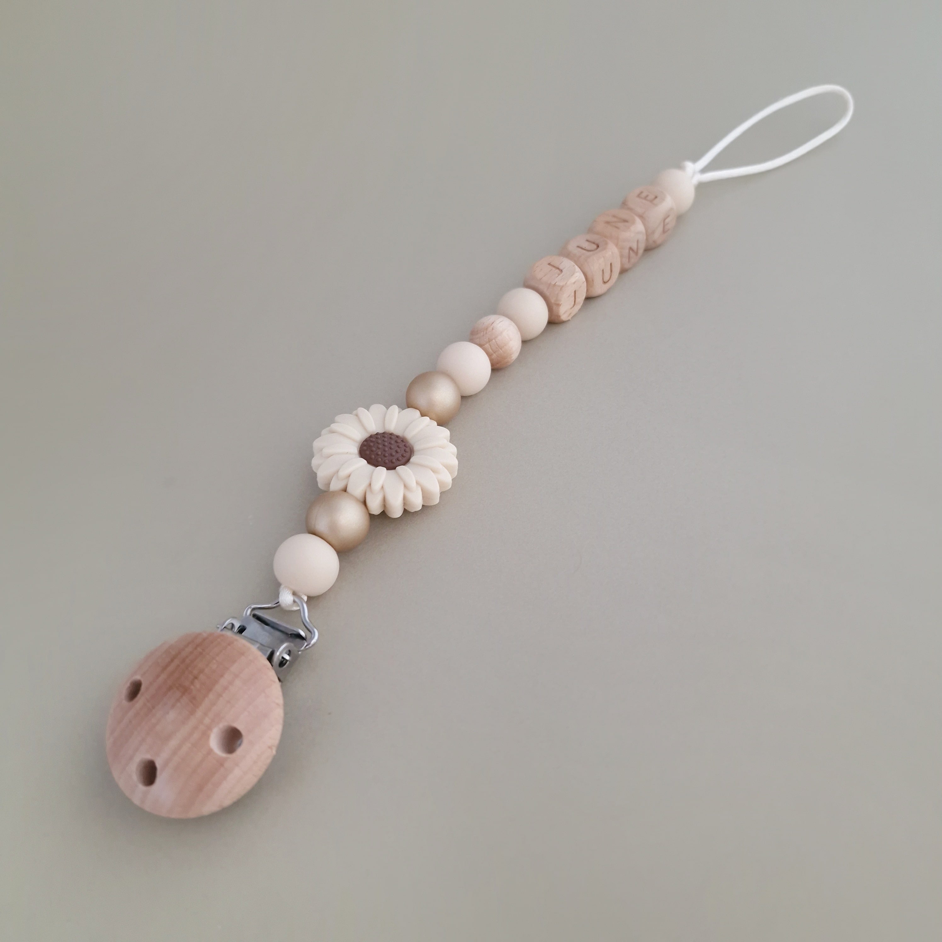 Speenkoord met naam van Studio Bambacht met bloem in de kleuren beige en goud