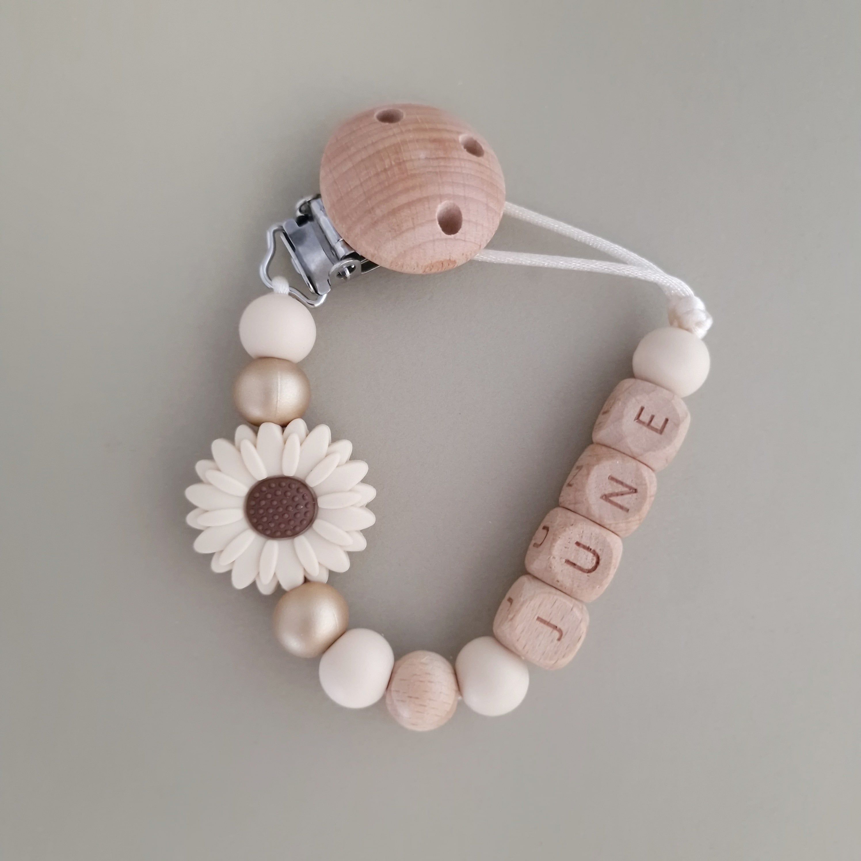 Speenkoord met naam van Studio Bambacht met bloem in de kleuren beige en goud