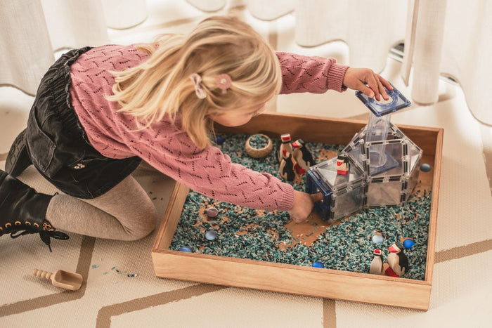 Passief en actief speelgoed gemixt in een houten speelbak