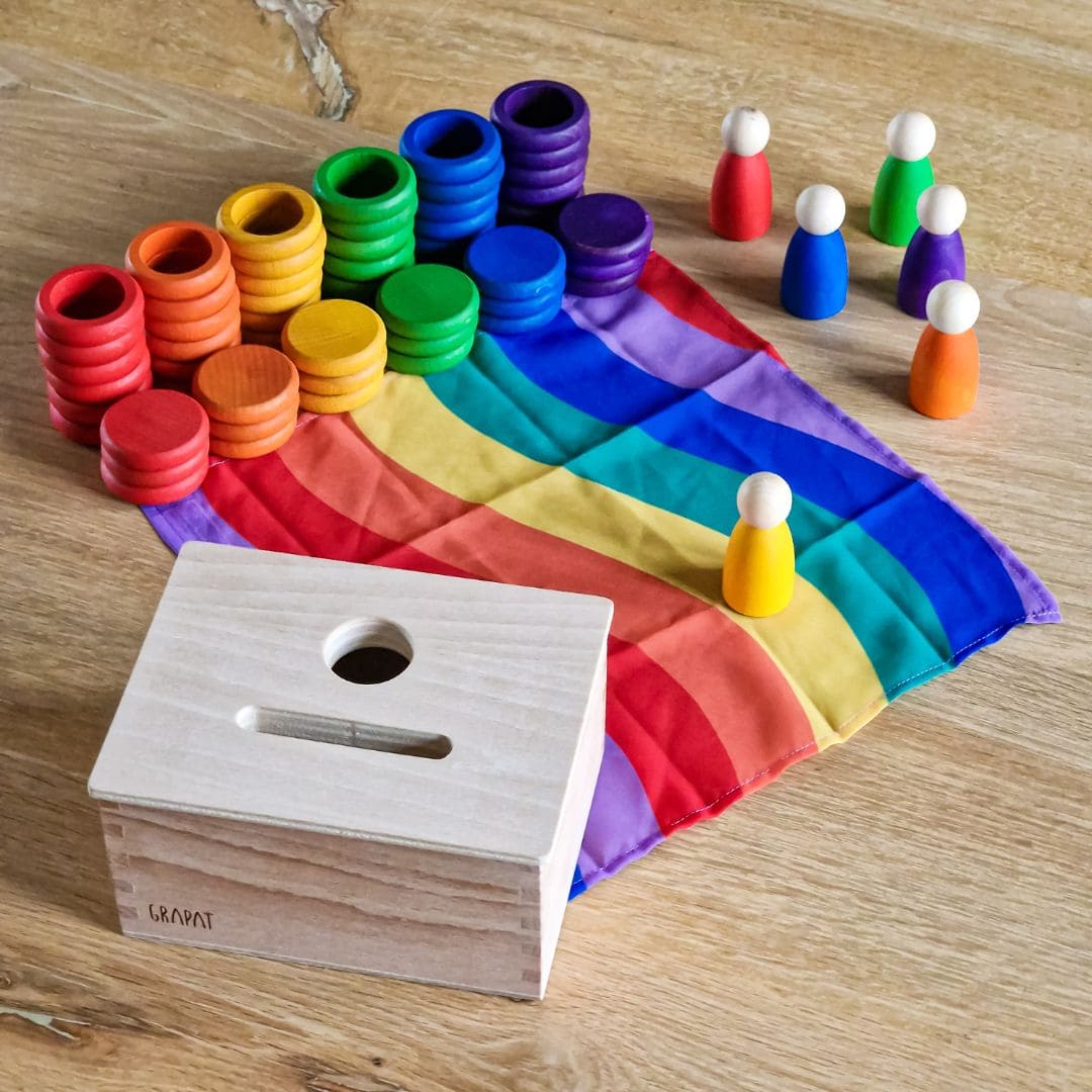 Open einde starterspeelset voor 0-2 jaar met objectpermanentiebox, speeldoek en grapat houten ringen, munten en poppetjes om objectpermantie te stimuleren en uit te nodigen tot fantasierijk en zelfstandig spel