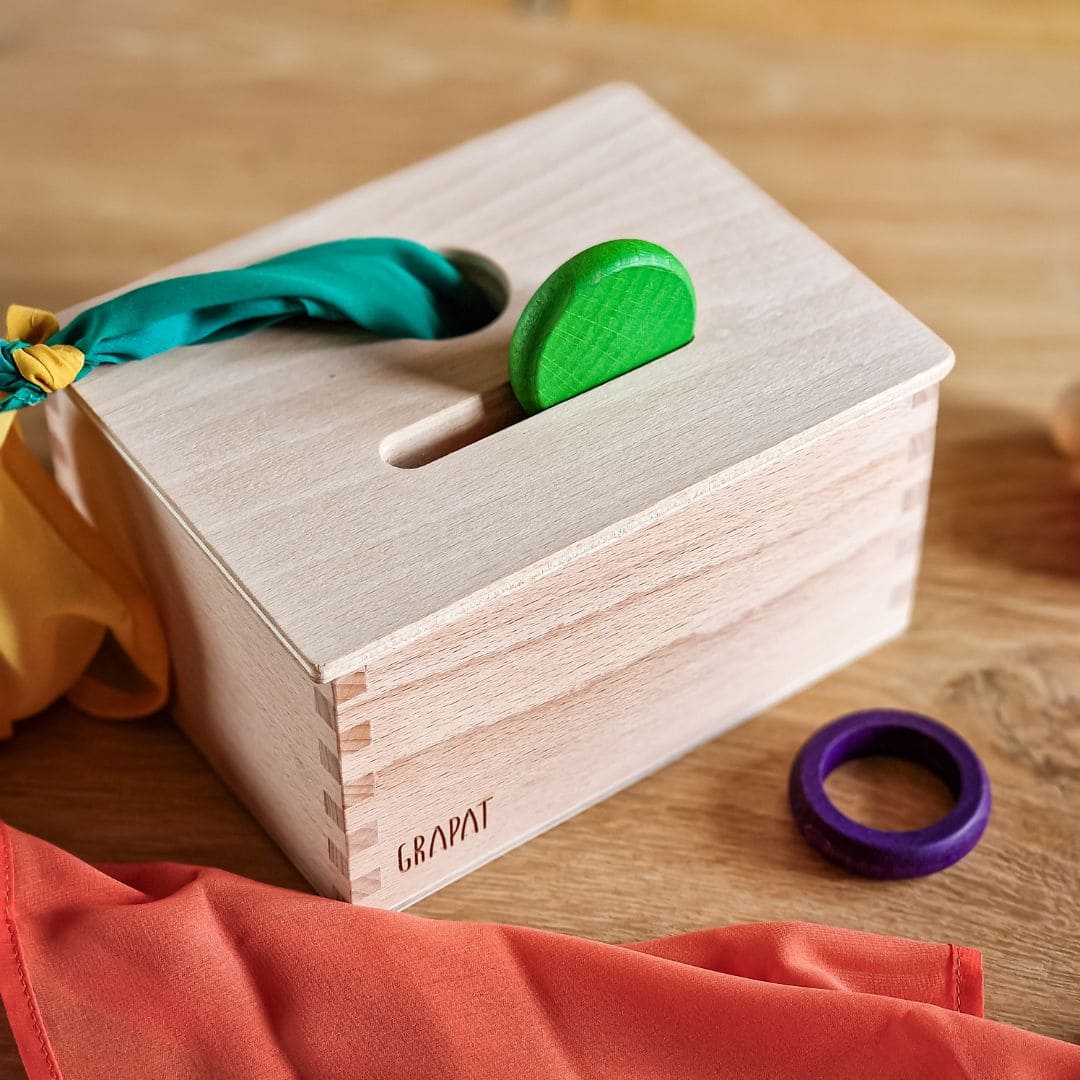 Open einde starterspeelset voor 0-2 jaar met objectpermanentiebox, speeldoek en grapat houten ringen, munten en poppetjes om objectpermantie te stimuleren en uit te nodigen tot fantasierijk en zelfstandig spel