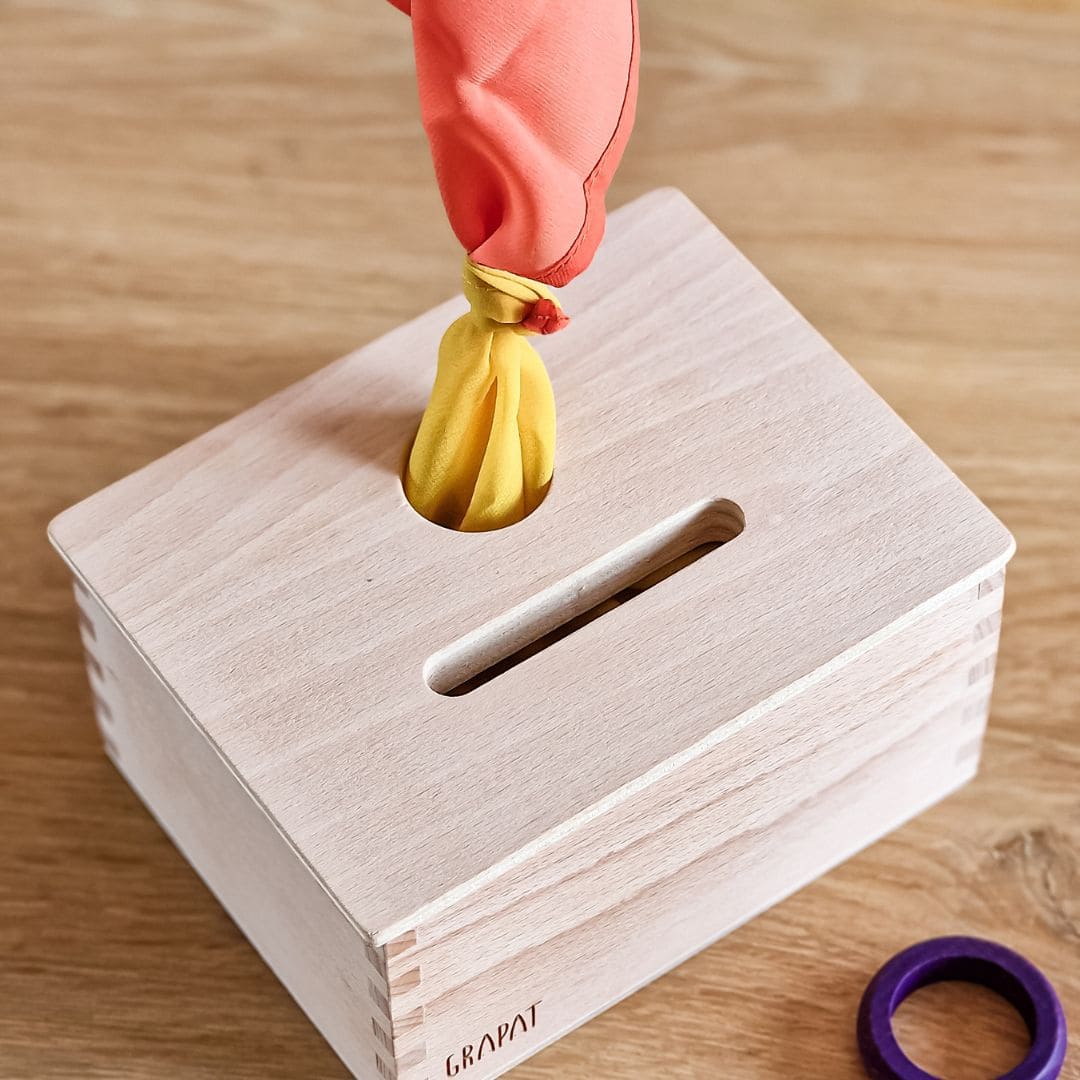 Open einde starterspeelset voor 0-2 jaar met objectpermanentiebox, speeldoek en grapat houten ringen, munten en poppetjes om objectpermantie te stimuleren en uit te nodigen tot fantasierijk en zelfstandig spel